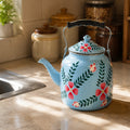 Decorative blue teapot with floral designs on a kitchen counter.