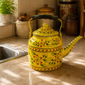 Yellow decorative teapot on a kitchen counter with a window and jars in the background