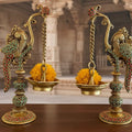 Decorative brass lamps with floral arrangements on a wooden surface, with a blurred architectural background.