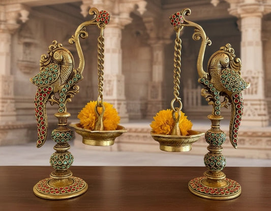 Decorative brass lamps with floral arrangements on a wooden surface, with a blurred architectural background.