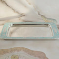 Silver tray with decorative edge on a marble surface