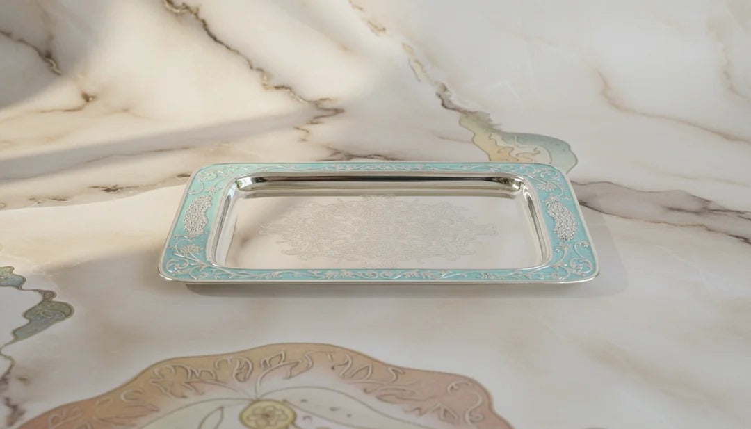 Silver tray with decorative edge on a marble surface