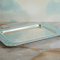 Silver tray with decorative border on a marble surface