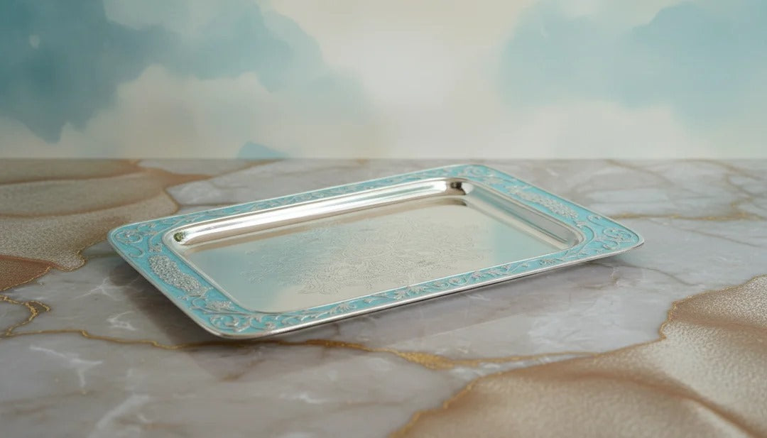 Silver tray with decorative border on a marble surface