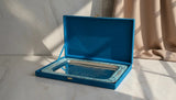 Blue jewelry box with a mirror on a marble surface