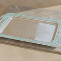 Decorative silver tray with green rim on a beige surface