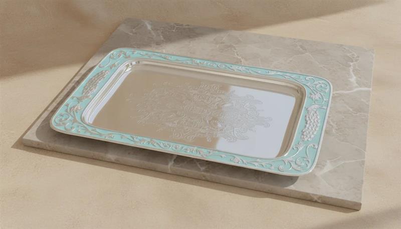 Decorative silver tray with green rim on a beige surface